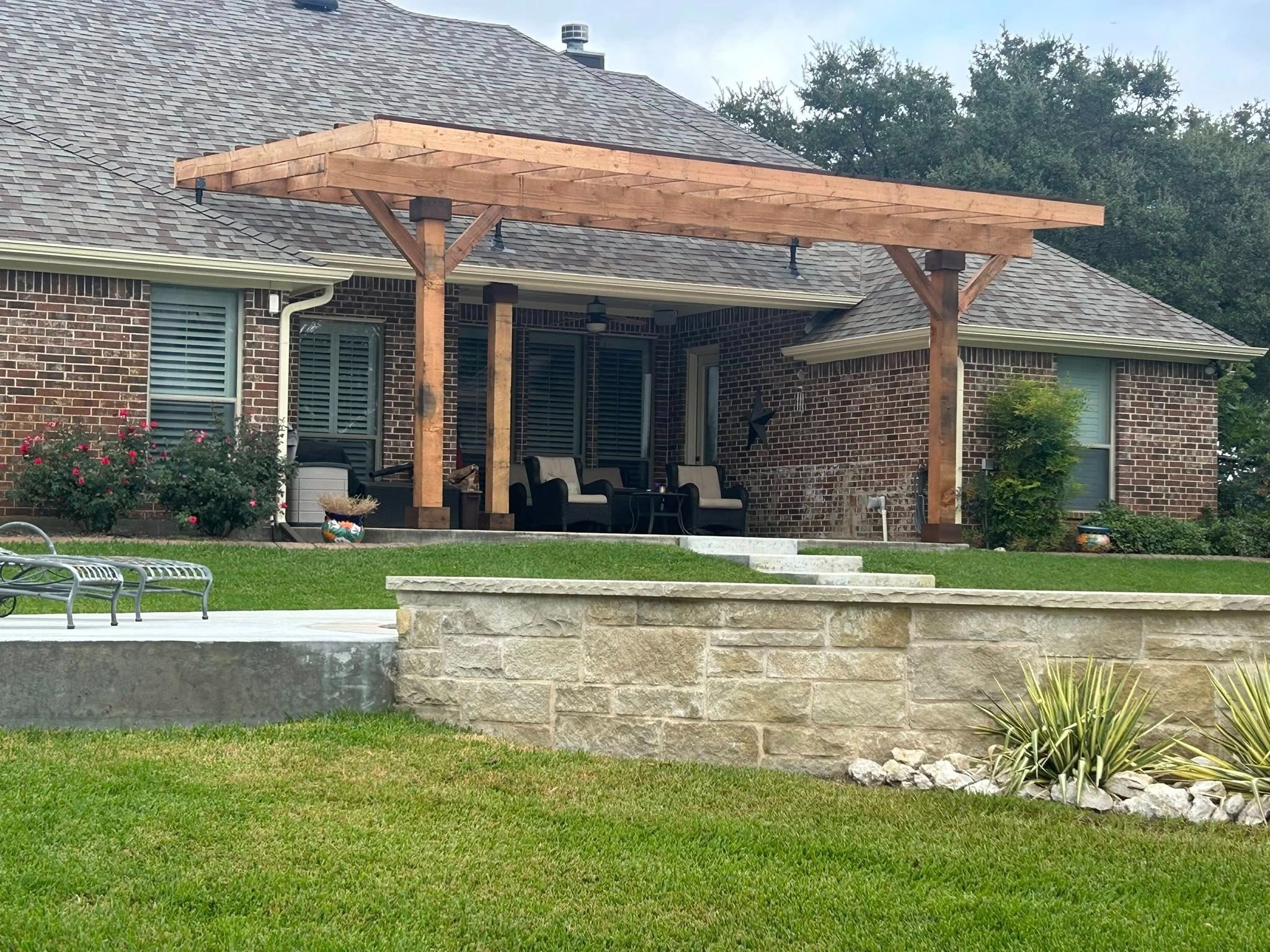 Pergola before staining — natural cedar on brick house