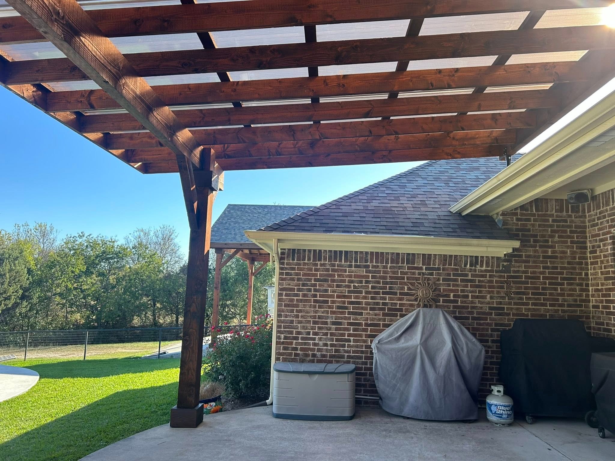 Under pergola — stained beams and brick house